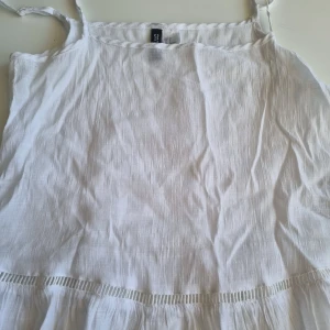 Vit linnetopp från H&M Divided - Säljer en söt vit linnetopp från H&M Divided i storlek XS. Toppen har tunna axelband och en luftig passform, perfekt för varma sommardagar. Den är gjord i ett lätt och bekvämt material med en fin detalj vid nederkanten. Perfekt för en avslappnad sommarlook! 🌞