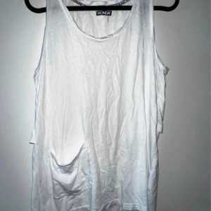 Vit ärmlös topp från Monki - Säljer en vit ärmlös topp från Monday i storlek S och är i bra skick. Toppen har en avslappnad passform och knappar bak för en extra detalj. Perfekt för sommardagar eller som ett basplagg i garderoben. Passar till både jeans och kjol!