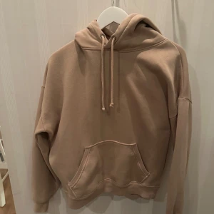 Beige hoodie från BikBok - Säljer en supermjuk och bekväm beige hoodie från BikBok i storlek S. Perfekt för mysiga höst- och vinterdagar. Den har en klassisk känguruficka och justerbar huva med dragsko. Passar perfekt till vardagsoutfiten!