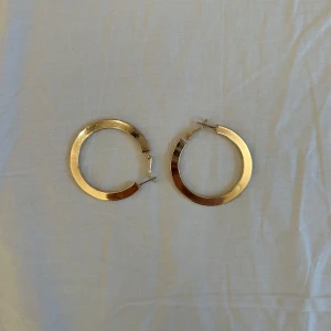Guldiga hoop-örhängen - Säljer ett par snygga guldiga hoop-örhängen i mycket bra skick. De är perfekta för att ge en elegant touch till vilken outfit som helst. Örhängena är i en klassisk rund form och har en enkel stängning. Perfekta för både vardag och fest! 5,5cm i deameter 