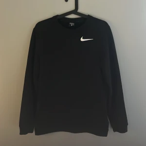 Svart Nike sweatshirt  - Säljer en svart sweatshirt från Nike i Dri-Fit material. Perfekt för träning eller vardagsbruk med en stilren design och den klassiska Nike-loggan på bröstet. Tröjan är i mycket bra skick och har en normal passform.