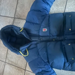 Fjälräven jacka mörkblå - Endast använd 1 vinter! Storlek xs, gamla modellen, säljer billigt då den har effekter. Skriv vid minsta lilla!!(snabb affär)