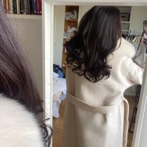 Beige kappa med pälsdetaljer - Säljer en superfin beige kappa med pälsdetaljer på kragen. Den har ett bälte i midjan för en snygg passform och långa ärmar. Perfekt för vintern. Använd fåtal gånger har prislappen kvar. Är i nyskick ! Kappan är i ull och kashmir. 