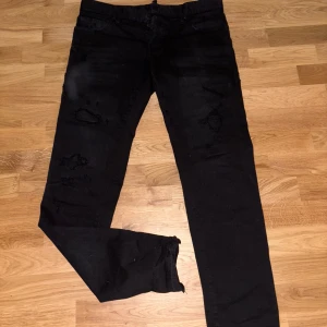 Svarta jeans från Dsquared2 - Säljer ett par feta svarta jeans från Dsquared2 i bra skick. De har en snygg, distressed look med slitningar på framsidan.  Passar bra till allt. Vet faktiskt inte nypriset till dessa.