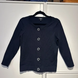 Mörkblå unik kofta - Säljer supercool mörkblå finstickad kofta i storlek S. Den har unika knappar som ger en cool touch och är perfekt för både vardag och fest. Koftan är i mycket bra skick och har långa ärmar. Perfekt året runt!