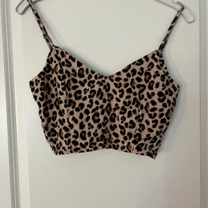 Leopardmönstrad linnetopp - Snygg leopardmönstrad linnetopp med smala axelband och knytning i ryggen. Perfekt för en somrig dag eller en utekväll. Toppen har en tight passform och är i mycket bra skick.