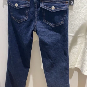 Mörkblå jeansbyxor - Snygga mörkblå jeansbyxor med hög midja och raka ben. De har klassiska fem fickor och knappar fram. Perfekta för både vardag och fest!