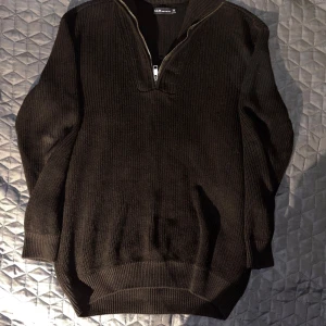 Svart stickad tröja från S.C.W. - Säljer en svart stickad tröja från S.C.W. i storlek M. Tröjan har en dragkedja framtill och är perfekt för kyliga dagar. Den är långärmad och har en ribbad struktur som ger en snygg look. Passar både till vardags och lite finare tillfällen.