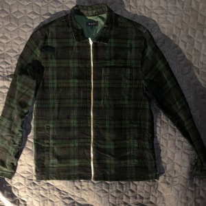 Grön rutig overshirt från Riley - Säljer en snygg grön rutig overshirt från Riley i storlek L. Den har en dragkedja framtill och är perfekt för höst och vår. Materialet känns mjukt och bekvämt, och den har långa ärmar. Perfekt för en casual look eller lager på lager-stil.