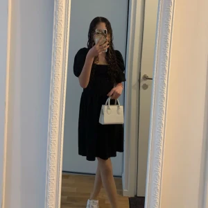 Svart klänning med puffärmar - Säljer en elegant svart klänning med puffiga kortärmar. Perfekt för både vardag och festliga tillfällen. Klänningen har en smickrande passform och är gjord i ett bekvämt material. Den är i mycket bra skick och redo för nya äventyr!