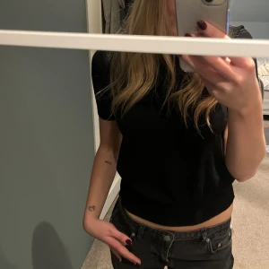 Svart kortärmad topp från Zara - Säljer en stilren svart kortärmad topp från Zara i storlek M. Perfekt för både vardag och fest! Toppen är i bra skick och har en normal passform. Passar till allt från jeans till kjol. 🖤