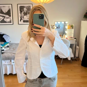 Vit kavaj - Snygg vit kavaj med knappar framtill. Perfekt för en stilren look. Kavajen har en klassisk krage och långa ärmar, vilket gör den idealisk för både formella och avslappnade tillfällen.