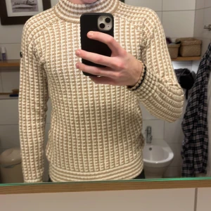 Beige stickad tröja från Pelle P - Säljer en snygg beige stickad tröja från Pelle P med ett unikt mönster. Tröjan har långa ärmar och en ribbad krage. Perfekt för kyliga dagar. Kontakta mig för mer info! Säljer då den är för liten 