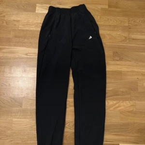 Svarta mjukisbyxor från Adidas - Säljer ett par svarta mjukisbyxor från Adidas med elastisk midja och diskret logga på benet. Perfekta för en avslappnad stil eller träning.