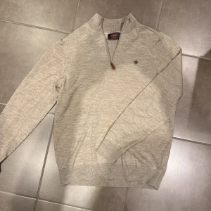 Morris zip - Säljer en stilren beige tröja från Morris med dragkedja och broderad logga på bröstet. Tröjan har en ribbad krage och är perfekt för både vardag och mer uppklädda tillfällen. Nypris: 1799kr