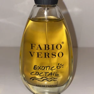 Fabio Verso Exotic Cocktail Eau de Parfum - Säljer en flaska Fabio Verso Exotic Cocktail Eau de Parfum. Den har en elegant, droppformad flaska med en gyllene vätska inuti. Perfekt för dig som älskar exotiska och fruktiga dofter. Flaskan har en svart kork och rymmer en doft som passar både dag och natt.