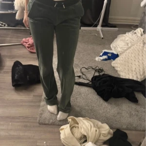 Gröna mjukisbyxor från Juicy Couture - Säljer ett par gröna mjukisbyxor från Juicy Couture i storlek XXS. Byxorna har en bekväm passform med dragsko i midjan och glittriga detaljer på baksidan. Perfekta för en avslappnad dag hemma eller en snabb tur på stan. Supermjuka och sköna!