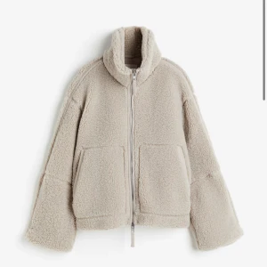 Beige teddyjacka med dragkedja - Supermysig beige teddyjacka som är perfekt för kyliga dagar. Den har en dragkedja framtill och stora fickor för extra komfort. Jackan är långärmad och har en hög krage som håller dig varm. Perfekt för höst och vinter!