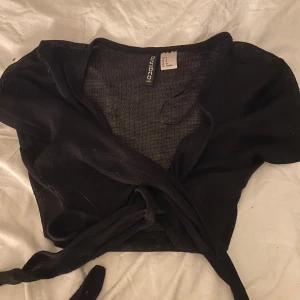 Svart knytblus  - Säljer en väldigt söt svart knytblus. Den är croppad och har en knytning framtill vid bysten pris kan diskuteras och skriv för frågor!🥰
