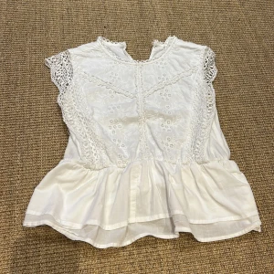 Egensydd vit blus  - Säljer en söt vit blus i mycket bra. Den har vackra spetsdetaljer och en volangkant som ger en romantisk känsla. Perfekt för vår och sommar! 💕