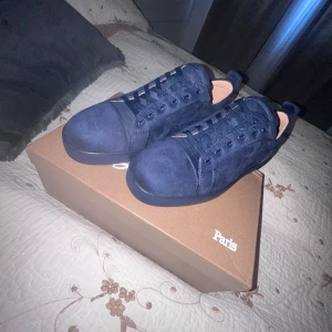 Louboutin  - Säljer ett par snygga mörkblå sneakers från Christian Louboutin. De är i mocka med den ikoniska röda sulan. Skorna har snörning och är i nytt skick. Perfekta för både vardag och fest!