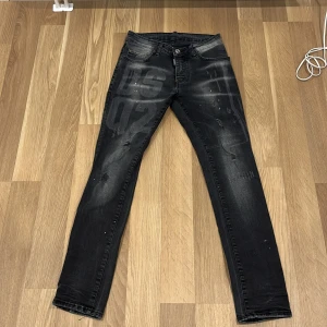 Svarta jeans från Dsquared2 - Säljer ett par svarta jeans från Dsquared2 i bra skick. De har en cool, sliten look med diskreta slitningar och en knappgylf. Perfekta för både vardag och fest! 🖤