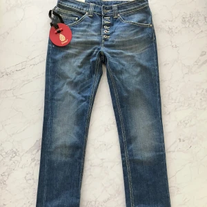 Blå jeans från Dondup - Snygga blå jeans från Dondup i modellen Surya. De har en klassisk femficksdesign med knappar i gylfen och en läderpatch baktill. Tillverkade i 100% bomull för en bekväm passform. Nypris ligger på 2600kr och är helt oanvända som ni ser då lappen hänger kvar. Köpta från butiken Cenino Donna. 