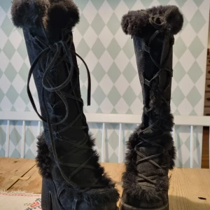 Demonias camel 311, Svarta vinterstövlar med pälsdetaljer - Snygga svarta stövlar med pälsdetaljer och snörning. Perfekta för kalla vinterdagar med en mysig och varm design.                                             Knappt använda.