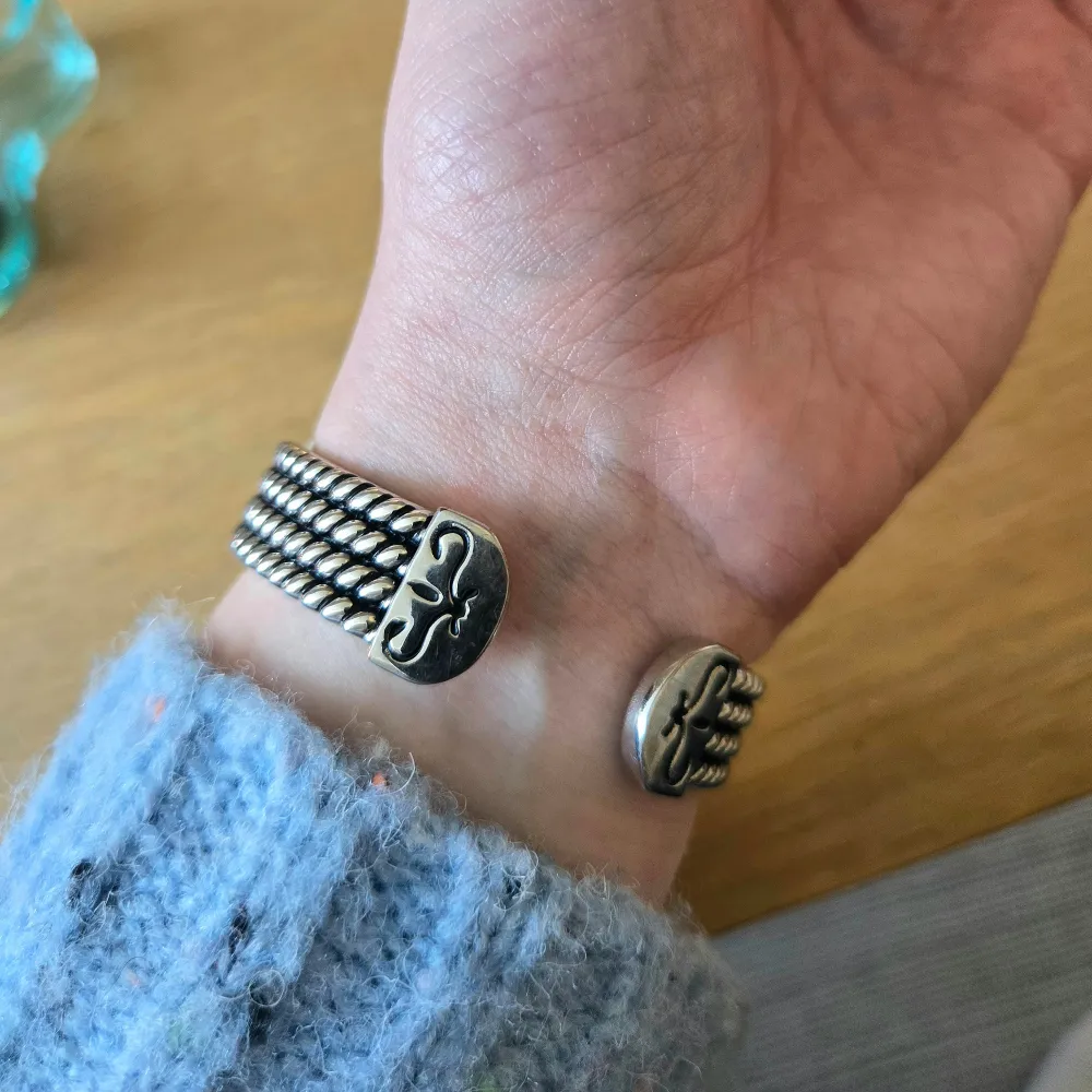 Säljer en stilren och elegant klocka i silverfärg med en rektangulär urtavla. Klockan har en vit urtavla med svarta siffror och visare. Armbandet är detaljerat med små dekorativa mönster. Perfekt för både vardag och fest!. Accessoarer.