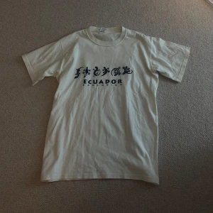 Beige t-shirt med Ecuador-tryck - Säljer en beige t-shirt med ett coolt tryck från Ecuador. Den är i bomull och har en normal passform. Size: L, fits mellan S och M!