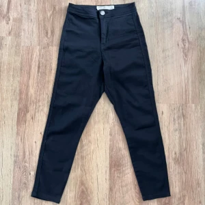 Svarta jeansbyxor från ASOS - Snygga svarta jeansbyxor från ASOS i en tight passform. Byxorna har en klassisk design med knapp och dragkedja framtill samt två bakfickor. Perfekta för en stilren look.