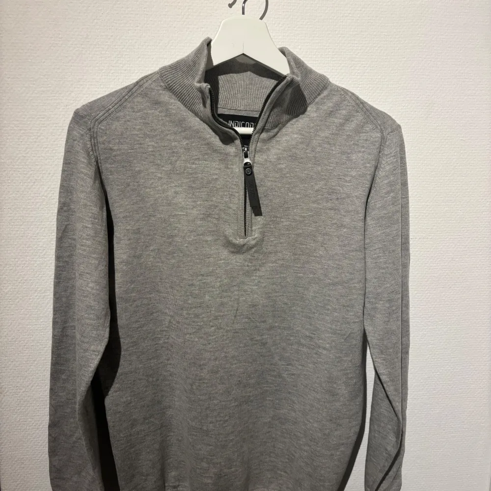 Snygg grå tröja från Indicode med halv dragkedja och ribbad krage. Perfekt för en stilren och bekväm look. . Neuletakit & Villapaidat.