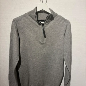 Grå halfzip från Indicode - Snygg grå tröja från Indicode med halv dragkedja och ribbad krage. Perfekt för en stilren och bekväm look. 