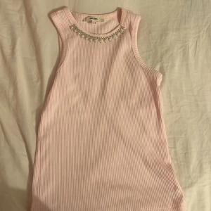 Rosa ribbad linnetopp från Koton - Säljer en rosa ribbad linnetopp från Koton. Toppen är ärmlös och har pärldetaljer vid halsringningen. 