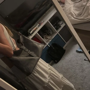 Grå axelväska med spänne - Snygg grå axelväska i syntetmaterial med justerbart axelband och dekorativt spänne med magnet framtill. Perfekt för att bära dina dagliga nödvändigheter med stil. Använd fåtal gånger, skriv för mer information 💕