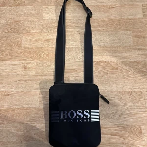 Hugo boss väska - Säljer min gamla Hugo boss väska eftersom att jag aldrig använder den längre.  Den är i väldigt bra skick eftersom att den använts 1-2 gånger och den är köpt från Boozt.