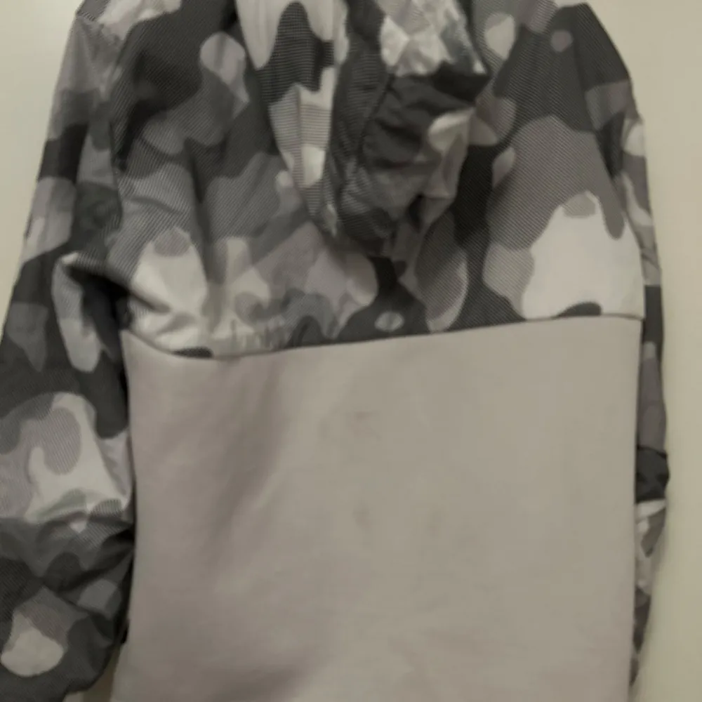 Säljer en supercool grå och vit camouflagejacka från BlackSquad. Den har en unik design med ett snyggt mönster och en dragkedja framtill. Perfekt för höst och vår när du vill sticka ut lite extra. Jackan är långärmad och har en normal passform. Den är i nyskick och redo för nya äventyr!. Jackor.