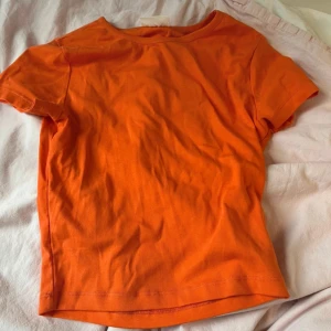 Orange t-shirt från Lindex - Säljer en snygg och enkel orange t-shirt från Lindex, basically basics-kollektionen. Perfekt för vardagsbruk med en skön passform. Den är kortärmad och gjord i mjukt material. Passar perfekt till både jeans och kjol!