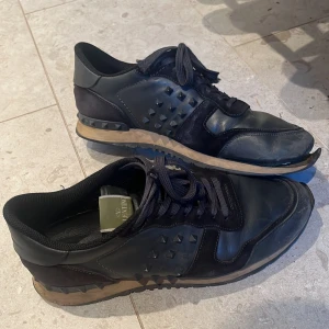 Valentino rockrunner 44 - Säljer ett par äkta valentino skor på grund av att utesulan håller på att gå sönder( går att fixa med lite lim) 6 spikar saknas totalt på båda skorna, 3 på ena skon och 3 på andra skon.  Kan självklart göra rent skorna vid köp och även byten!!  