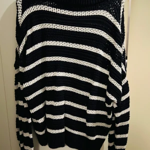 Svart och vit randig stickad tröja - Säljer en supermysig mörkblå och vit randig stickad tröja i storlek M. Perfekt för kyliga dagar med sin sköna och avslappnade passform. Tröjan har långa ärmar och en ribbad krage som ger extra värme. Ett måste för höst- och vintergarderoben!
