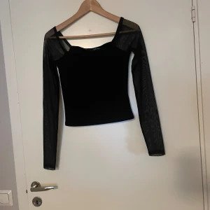 Svart långärmad meshtopp den na-kd - Snygg svart topp från NA-KD i storlek XXS. Den har långa ärmar och en stilren design, perfekt för både vardag och fest.