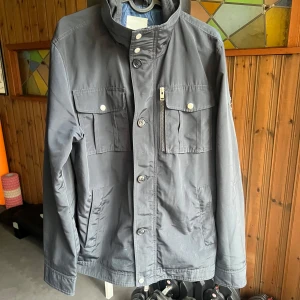 J.Lindeberg Field Jacket  - Säljer nu denna jackan från J.Lindeberg som är perfekt till hösten. Bra skick på jackan enbart någon fläck som lätt tvättas bort. Storlek medium och i en marinblå färg. Hör av er vid frågor eller funderingar. Priset är inte hugget i sten 