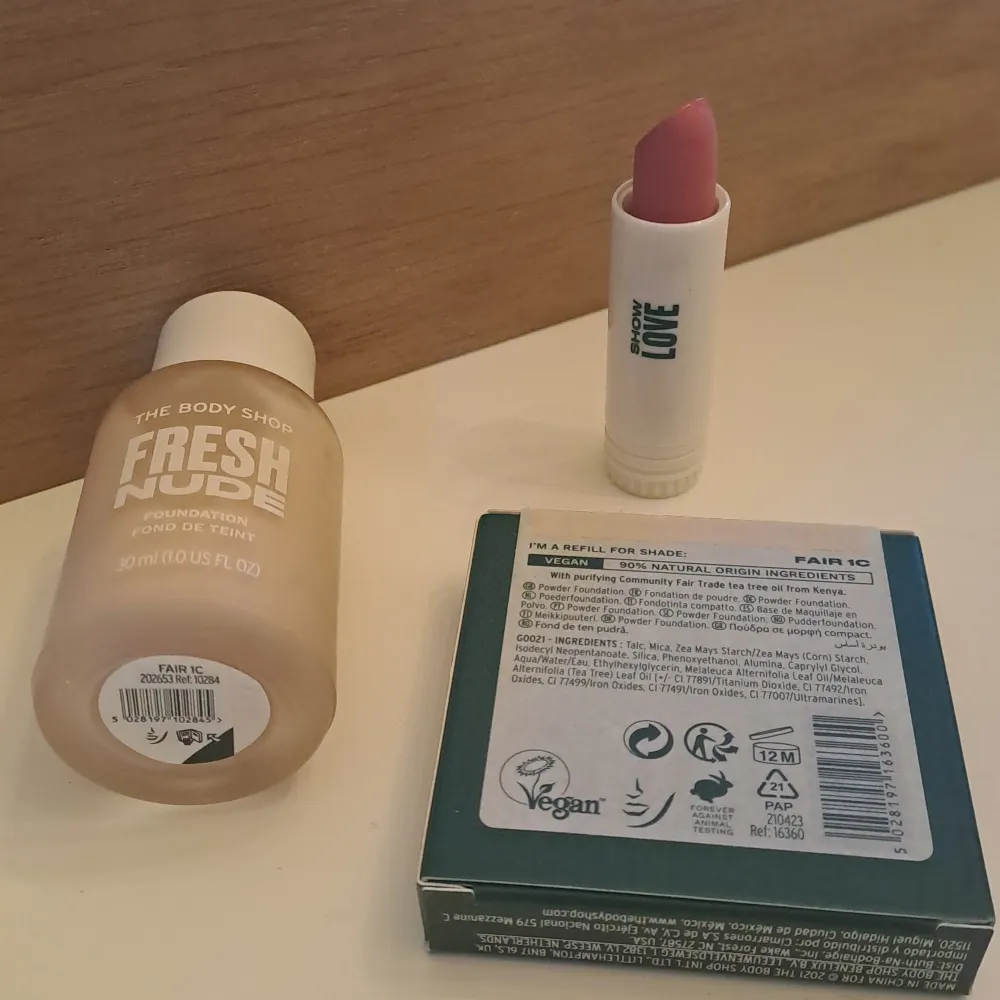 Säljer tre sminkprodukter från The Body Shop. Först har vi en foundation från serien Fresh Nude i nyansen Fair 1C, perfekt för en naturlig look. Sedan finns det en Tea Tree Face Base, en puderfoundation som är idealisk för att hålla huden matt och fräsch. Slutligen en läppbalsam i en mjuk rosa nyans från serien Love, som ger läpparna fukt och en lätt färg.. Skönhet.