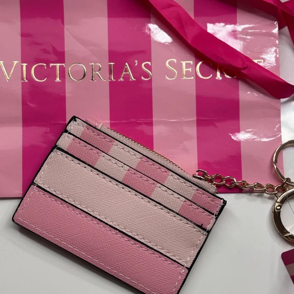 Säljer en superfin plånbok från Victoria's Secret. Den har en snygg kombination av rosa och beige ränder och är perfekt för att hålla dina kort och kontanter. Den är i nyskick och fick aldrig använda. Jom med ditt bud! 🌸. Väskor.