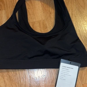 Svart sport-bh från ICANIWILL - Säljer en svart sport-bh från ICANIWILL. Den är perfekt för träning med sin bekväma passform och elastiska material. Den har en stilren design med ICANIWILL-loggan på sidan. Perfekt för gymmet eller löprundan!
