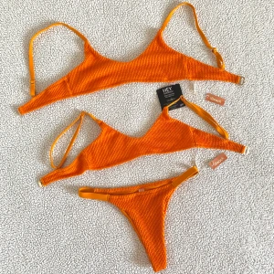 Nelly orange bikini - Orange bikini från Nelly. Två likadana överdelar, ena i storlek XS och andra i storlek S. Underdelen är i storlek S. Endast bikiniunderdelen är tvättad en gång. Aldrig använt, överdelarna är nya med prislappar kvar.