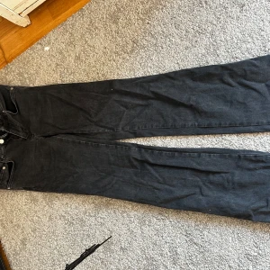 Svarta jeans - Säljer ett par svarta jeans i bra skick. De har en klassisk design med fem fickor och knappar i midjan. Perfekta för både vardag och fest!
