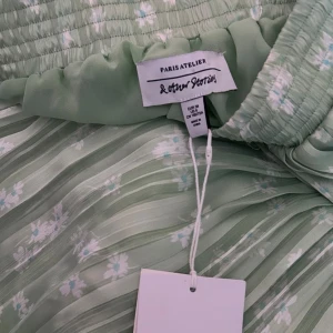 Grön siden kjol med blommor på  - Helt oanvänd och ny kjol med lappen kvar! Kjolen är gjord av designern Paris Atelier som designar kläder för & other stories. Med tanke på att kjolen inte är använd alls är prisen där efter…