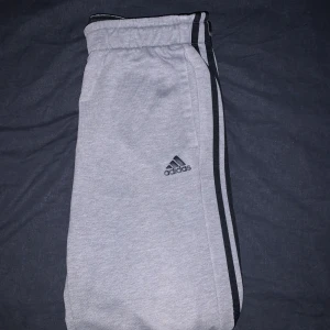 Adidas byxor  - Grå adidas byxor med svarta detaljer.  Storlek M  Mycket bekväma. Säljes i befintligt skick därav priset. Helt klart prisvärd. Fynda! 