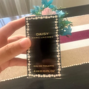 Daisy Eau de Toilette från Marc Jacobs - Säljer en söt liten flaska Daisy Eau de Toilette från Marc Jacobs. Förpackningen är svart med små vita blommor runt kanterna, vilket ger en fräsch och blommig känsla. Perfekt för att ha med sig i väskan! Flaskan rymmer 4 ml.